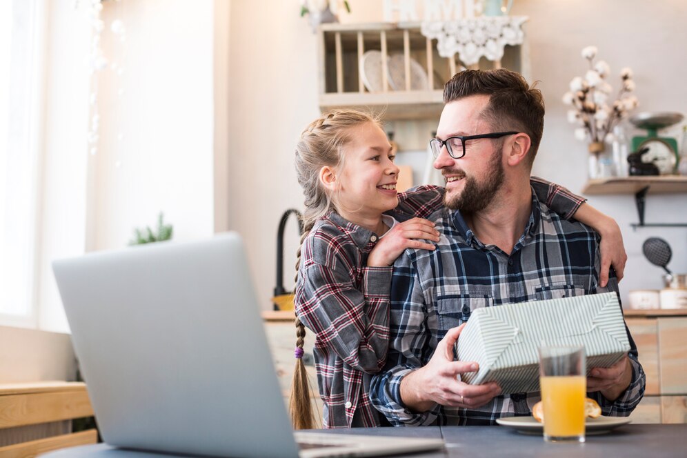 Filha presenteia o pai enquanto ele trabalha de home-office.